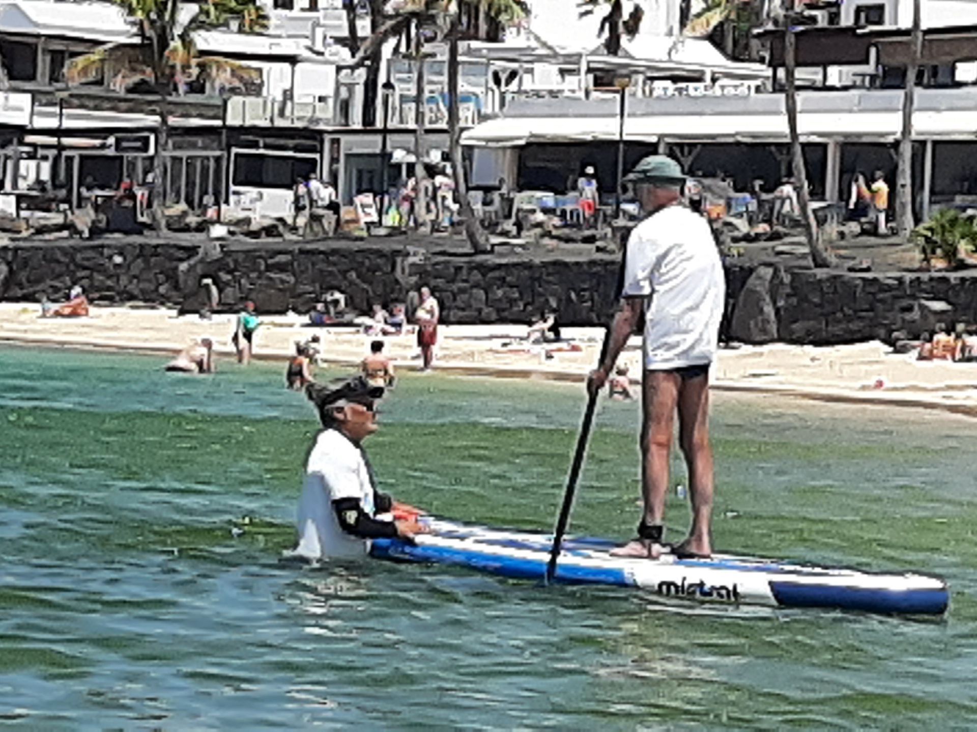 A man is standing on a paddle board in the water.
