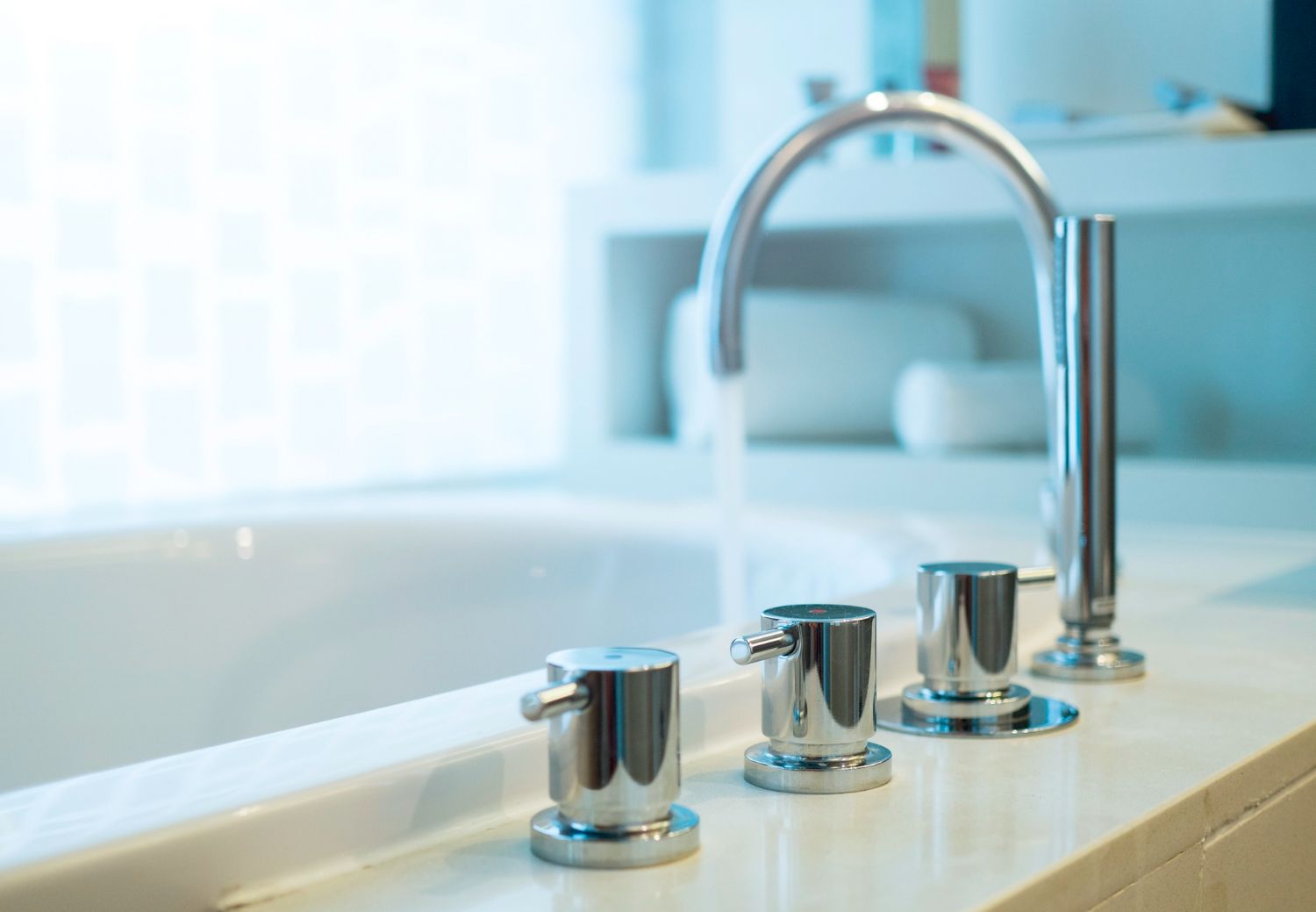 Modern bathroom sink with chrome faucet and three knobs beside a bathtub
