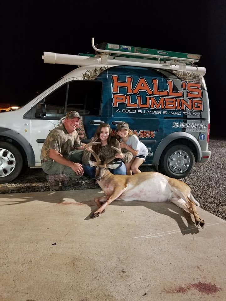 Plumbing van at night with three people crouching beside a dog lying on the pavement