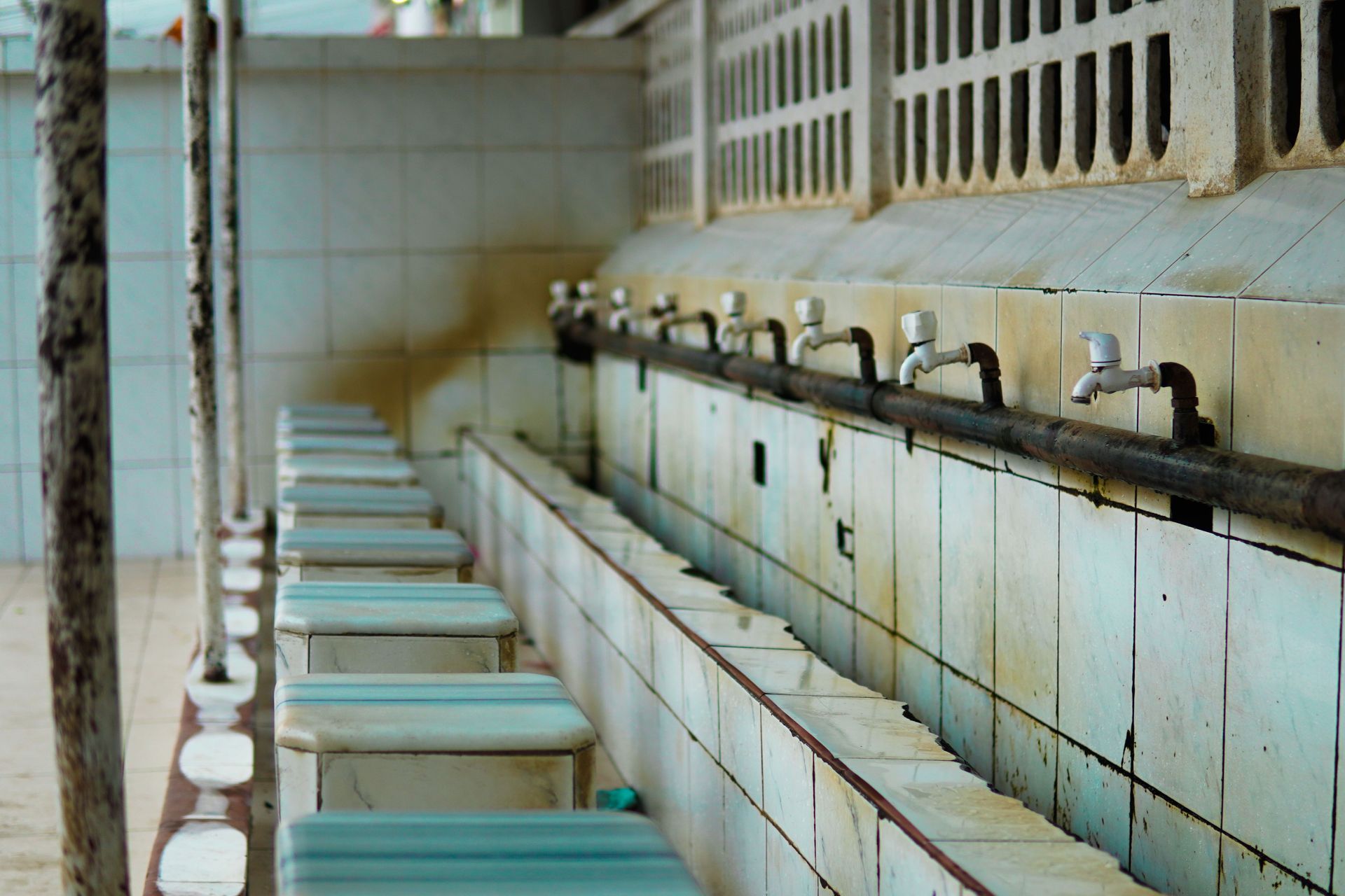 Row of blue sinks and white tiled washbasins in a long restroom or washing area