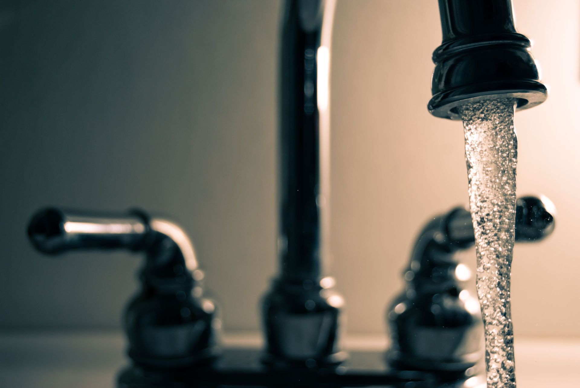 Running kitchen faucet with water pouring into a sink