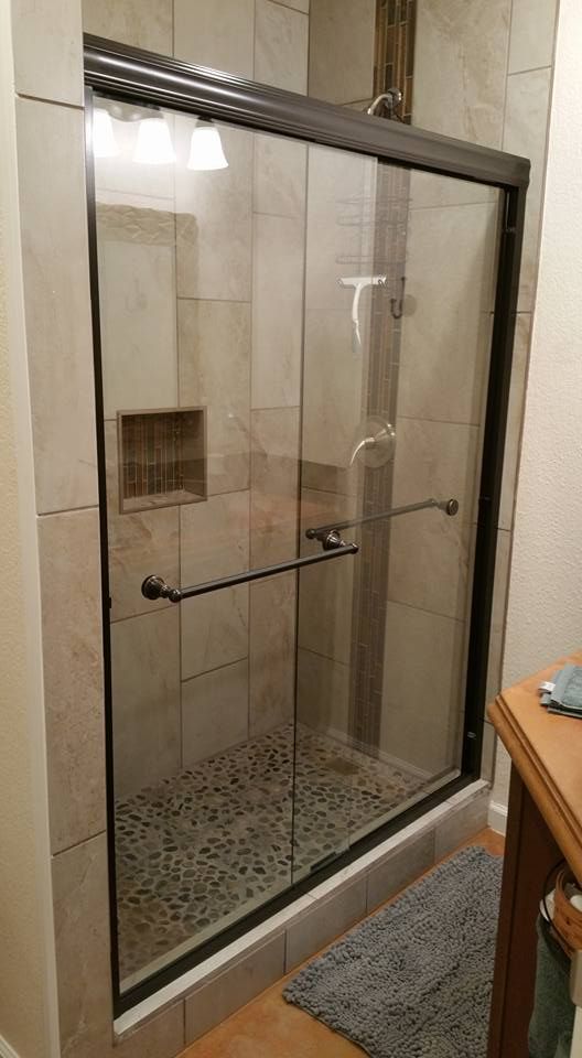 A bright bathroom featuring a white vanity with a quartz countertop, framed mirror, and a tiled walk-in shower.