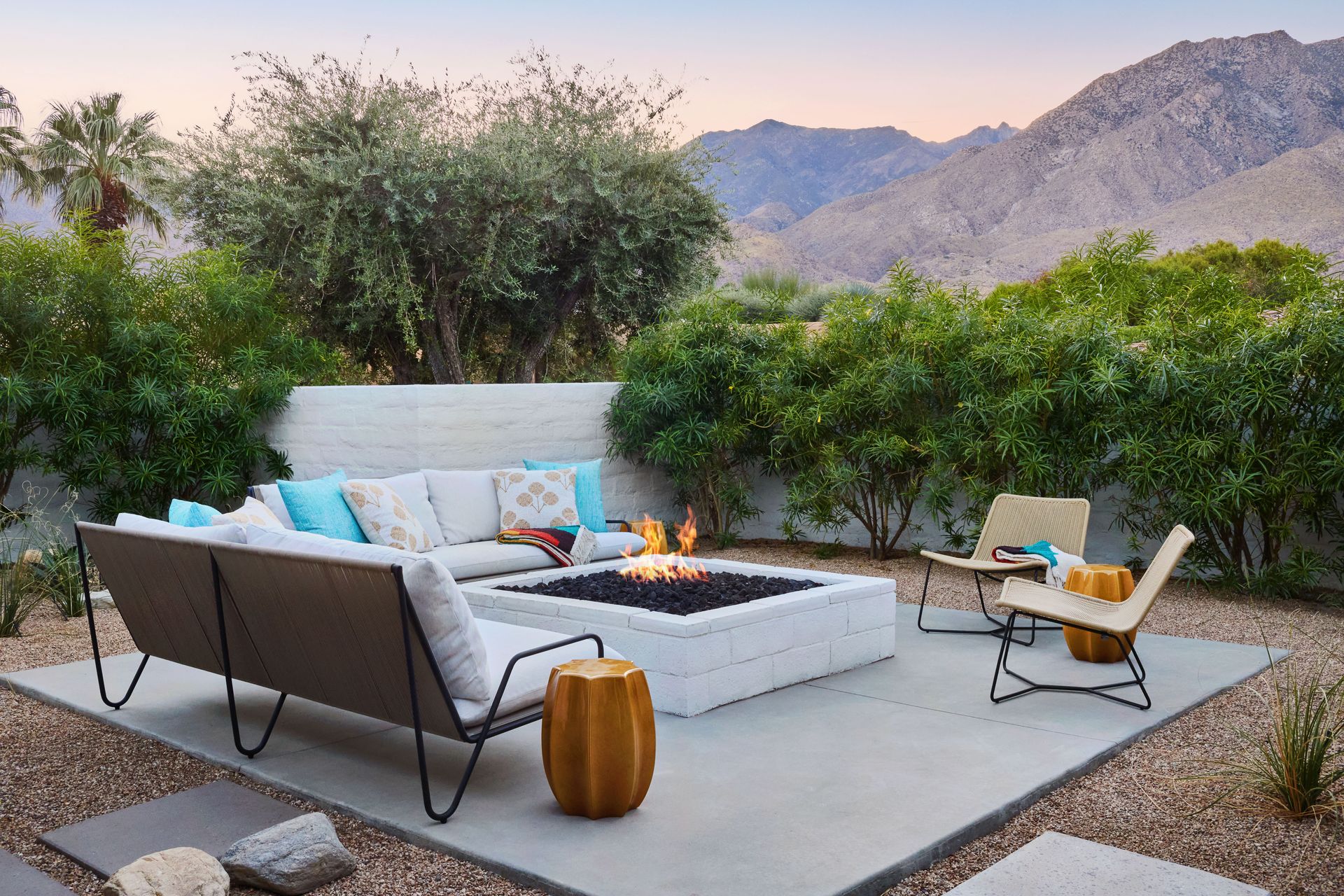 Outdoor patio with fire pit, sectional sofa, and mountain backdrop.