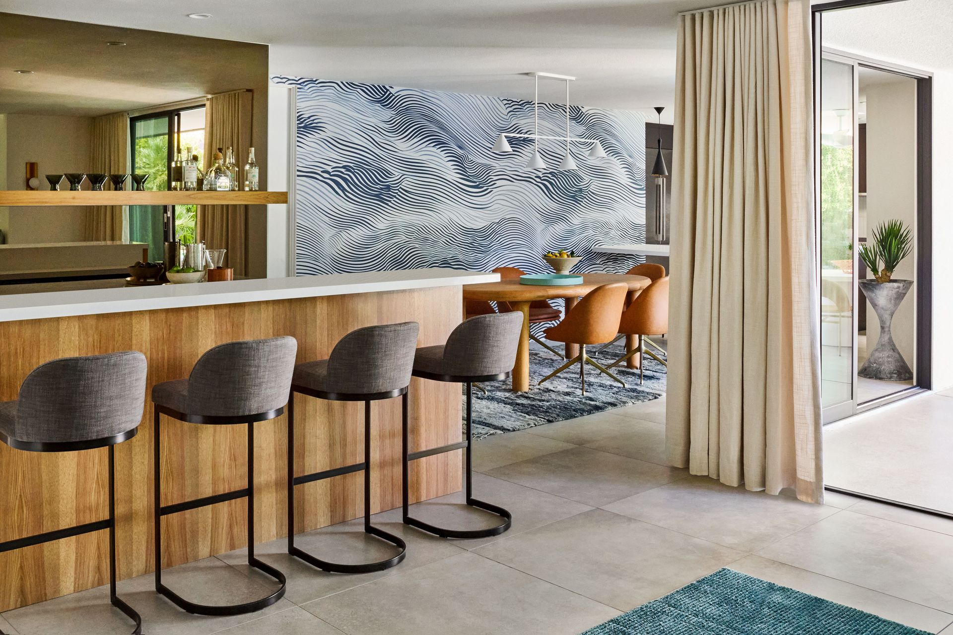 Bar stools at a counter with a wood base. Dining area has a patterned wall and table.