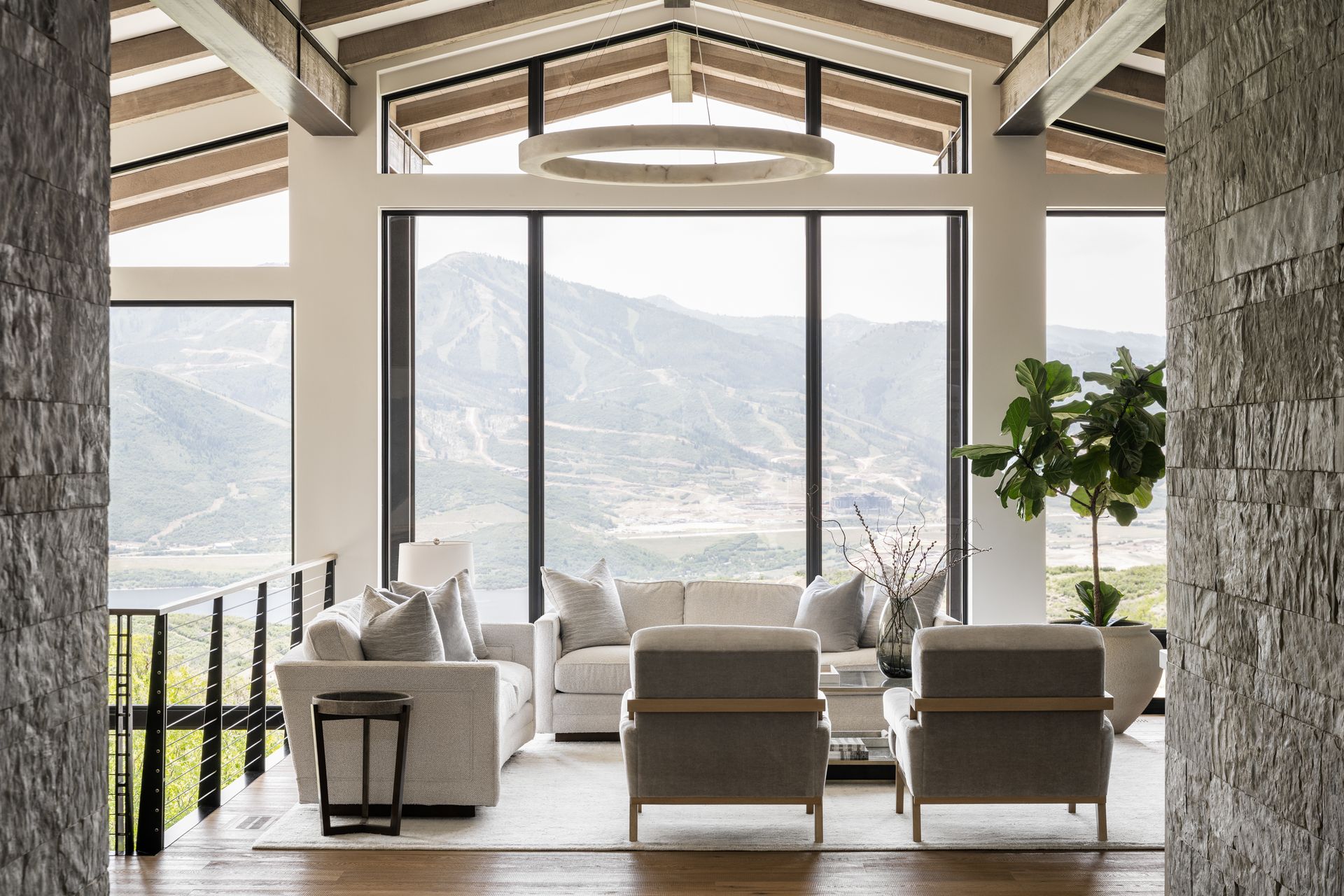 Living room with mountain view through large windows, modern furniture, and wood beams.