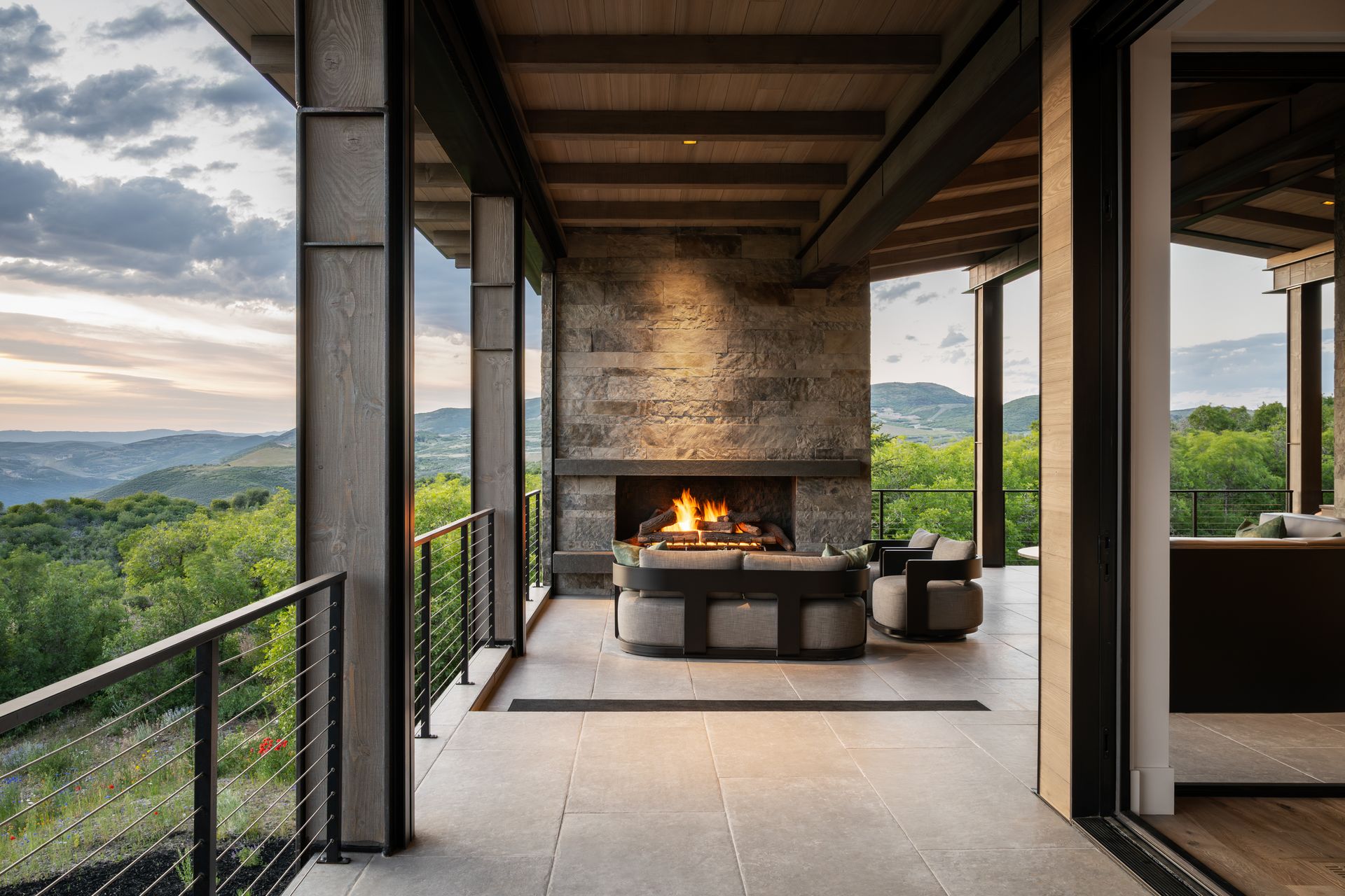 Outdoor living space with fireplace, sofas, and mountain views.