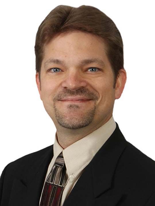 A man in a suit and tie is smiling for the camera