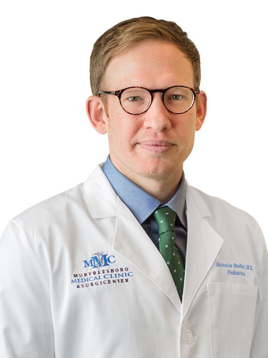 A man wearing a white lab coat and a green tie