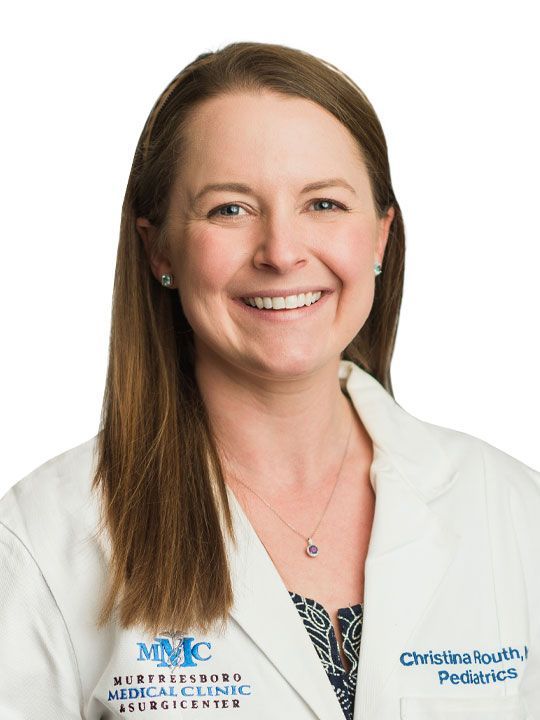 A woman in a white lab coat is smiling for the camera