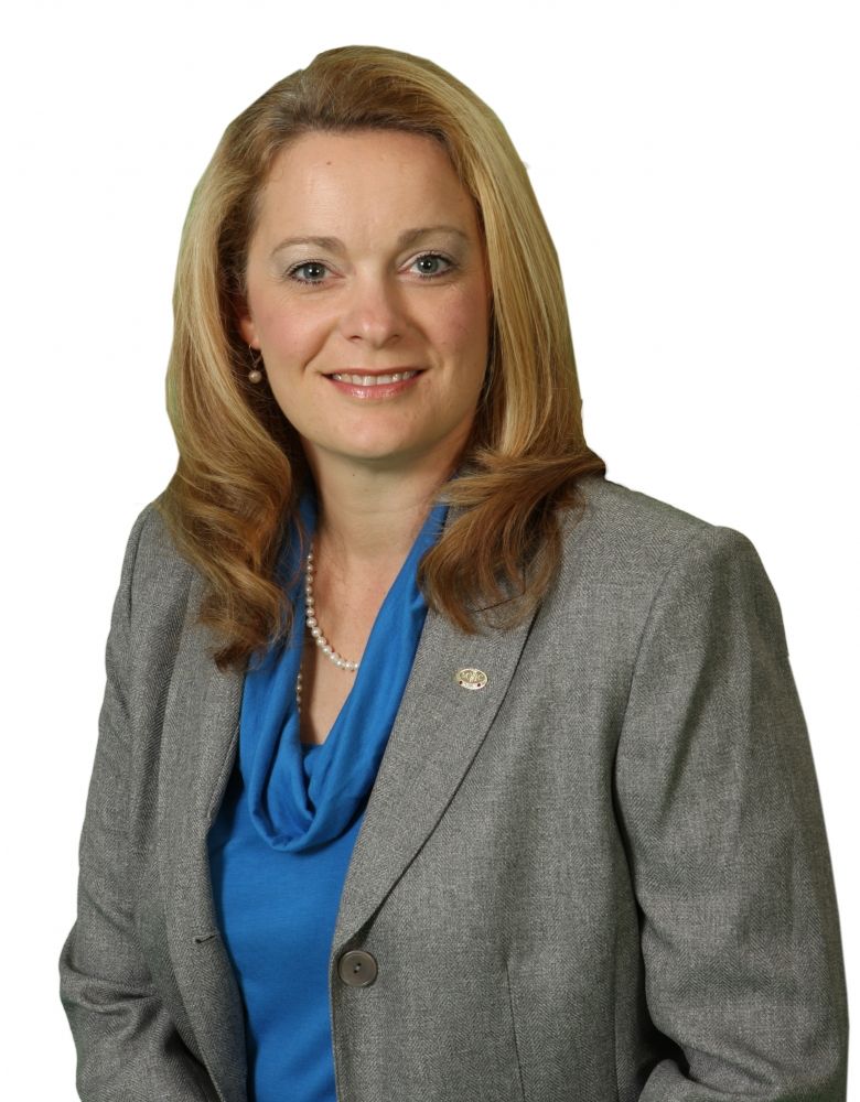 A woman wearing a grey jacket and a blue shirt