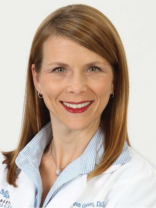 A woman wearing a white lab coat with the name anna green on it
