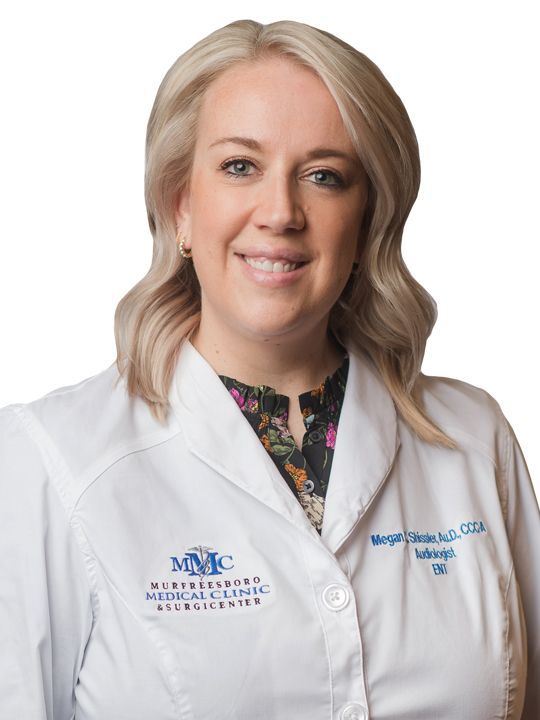 A woman in a white lab coat is smiling for the camera.