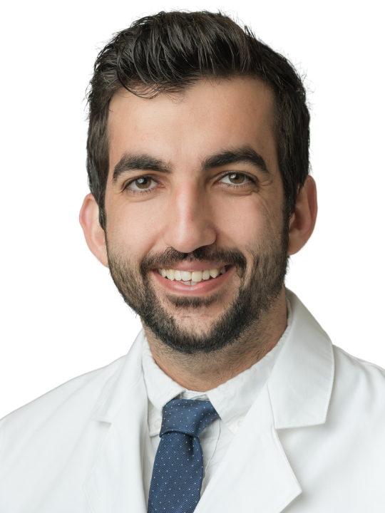 A man with a beard is wearing a white lab coat