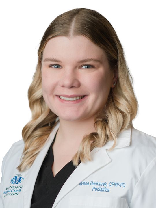 A woman in a white lab coat is smiling for the camera