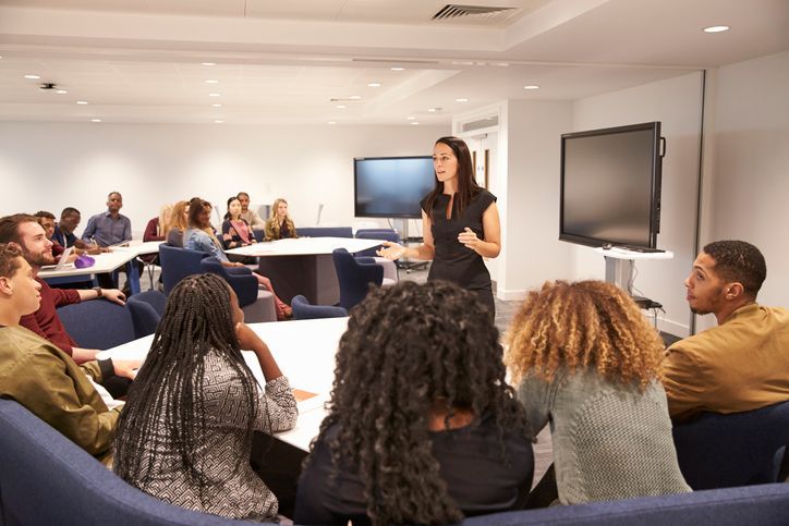 a woman is giving a presentation to a group of people
