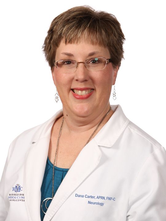 A woman wearing glasses and a white lab coat is smiling