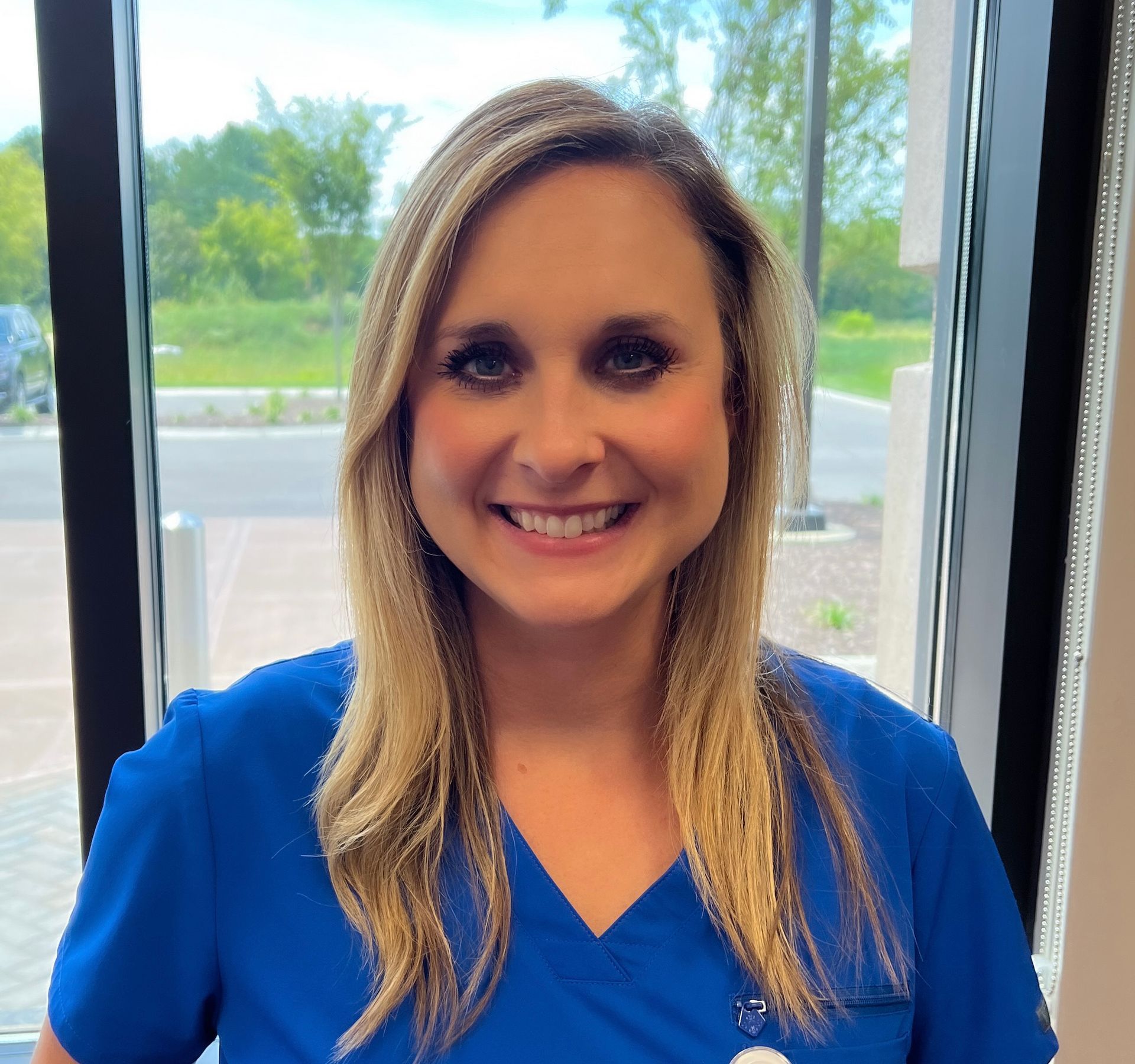 A smiling woman with a blue scrub top.