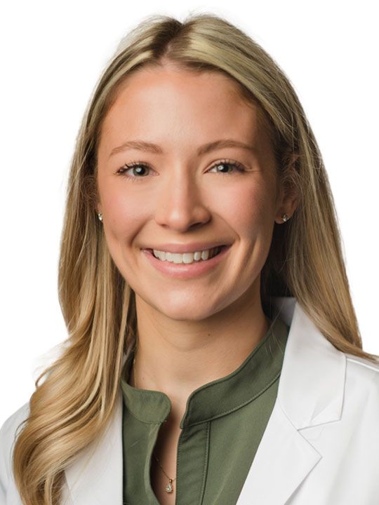 A woman in a white lab coat is smiling for the camera.