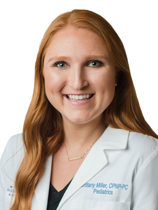 A woman in a white lab coat is smiling for the camera