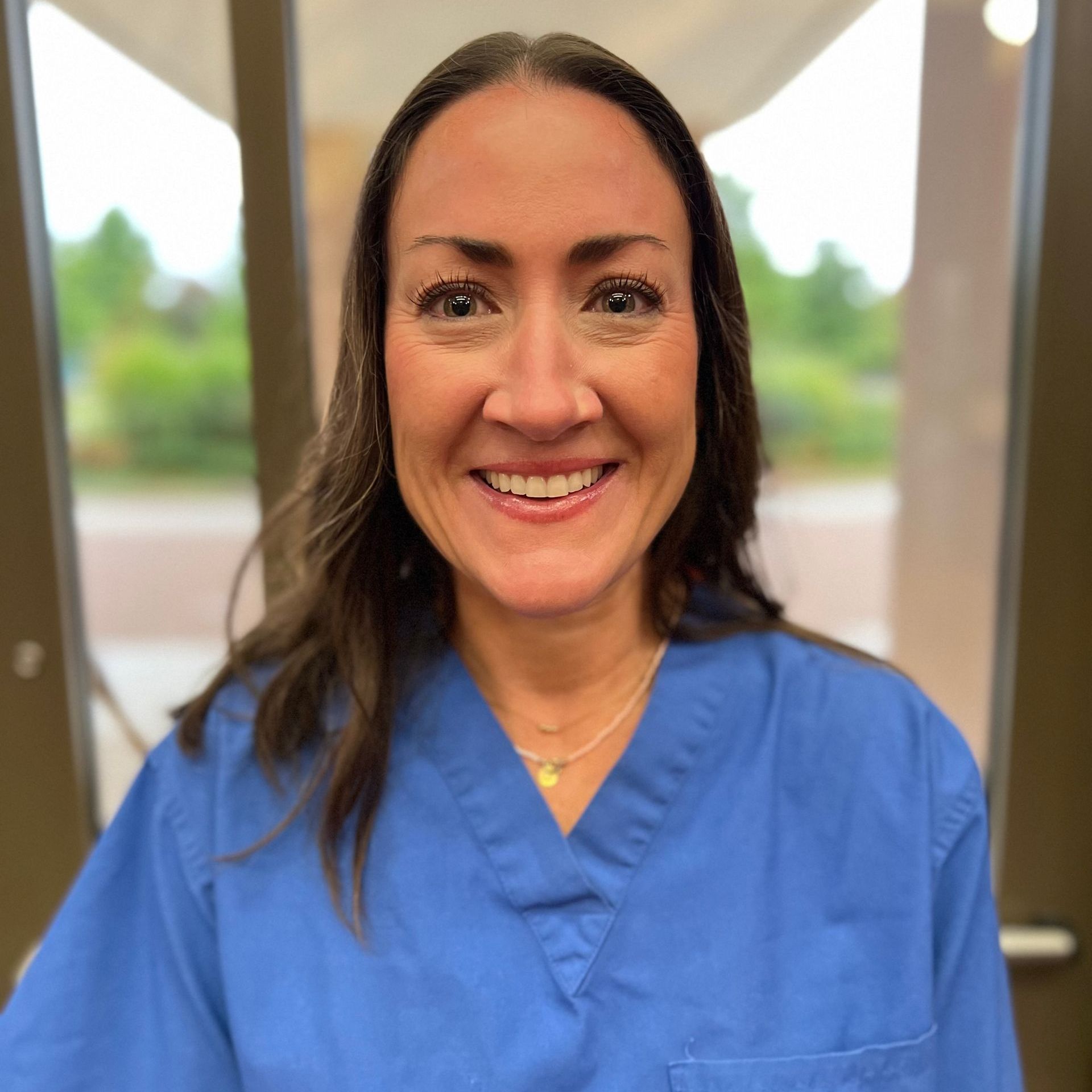 A woman is wearing a blue scrub top.