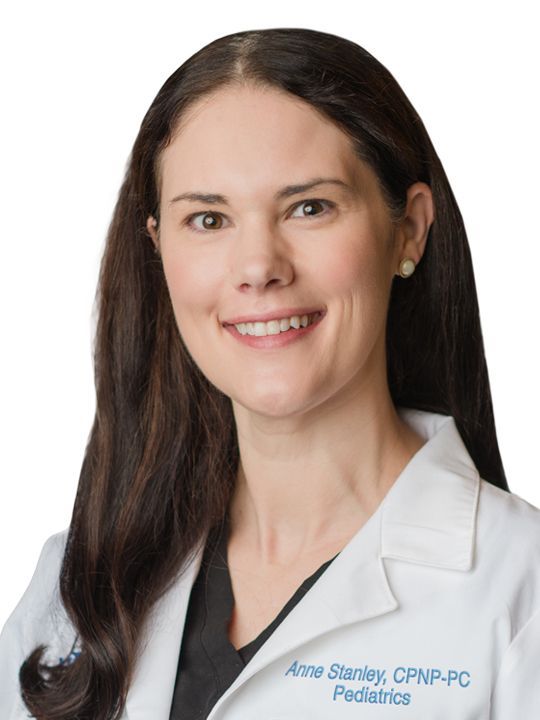 A woman in a white coat with the name anne stanley on it