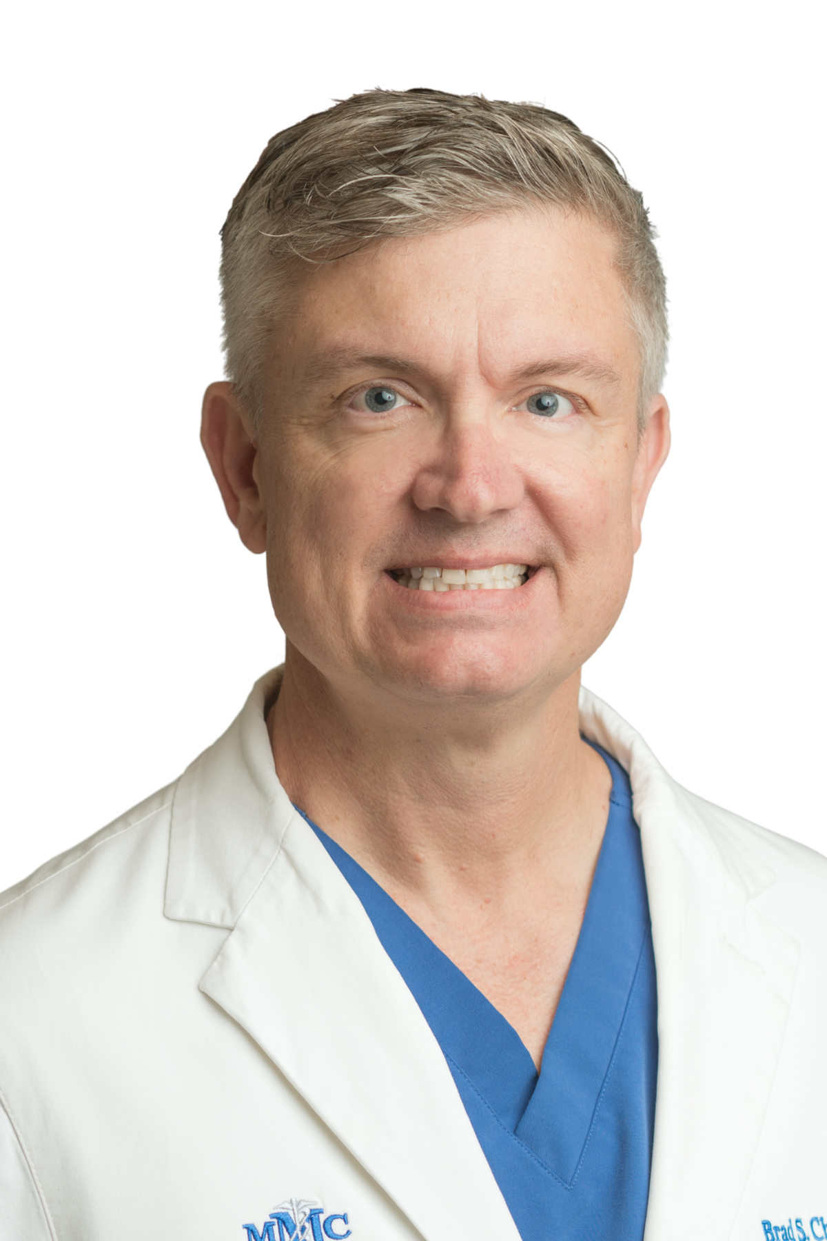A man in a white coat and tie smiles for the camera