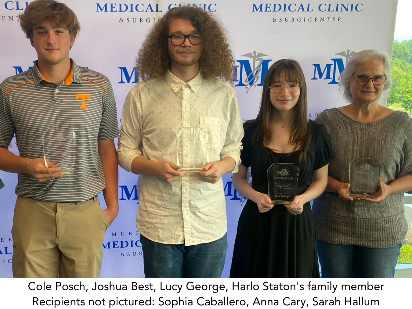 A group of people holding trophies in front of a medical clinic backdrop