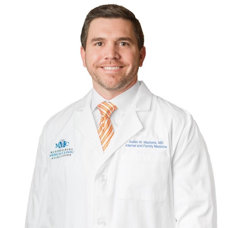 A man in a white coat and tie is smiling for the camera