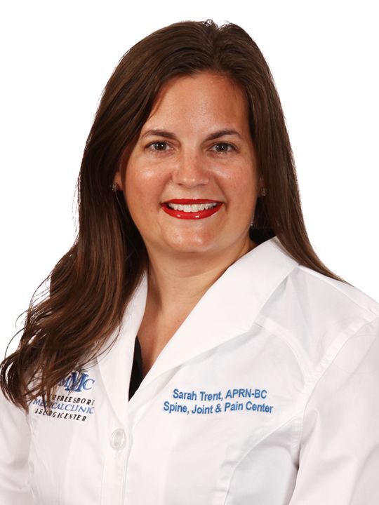 A woman in a white lab coat is smiling for the camera