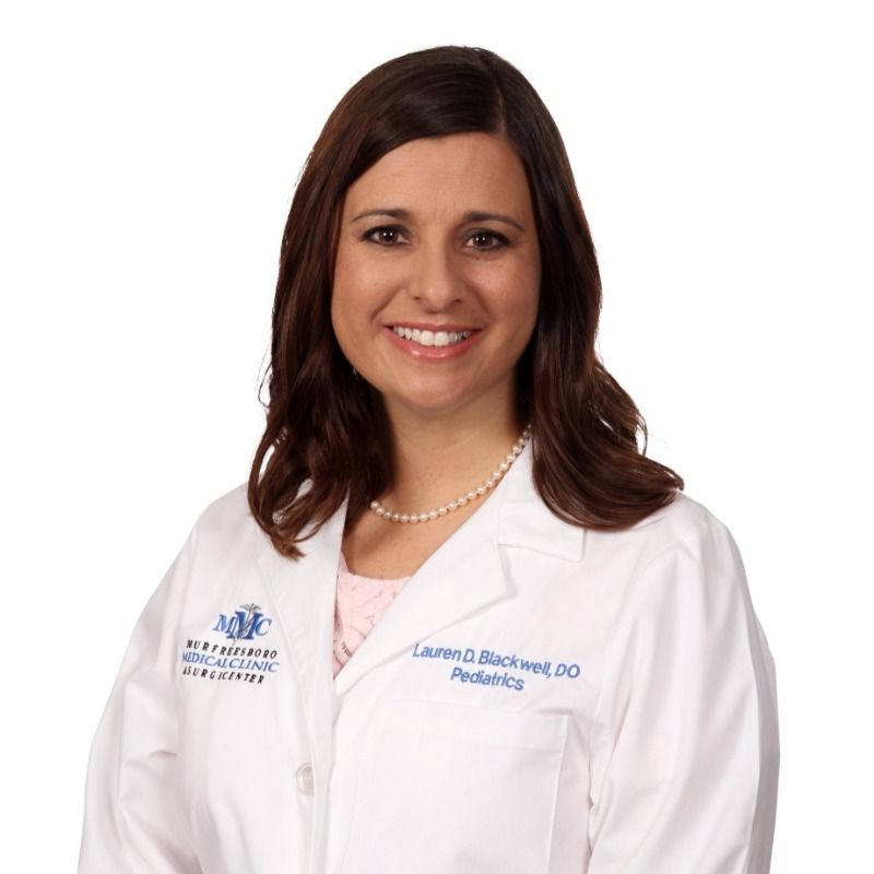 A woman wearing a white lab coat that says pediatrics on it