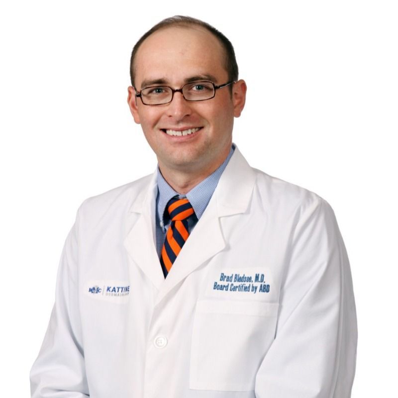 A man wearing a white lab coat and an orange tie