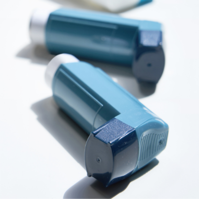 Three blue inhalers are sitting on a white surface