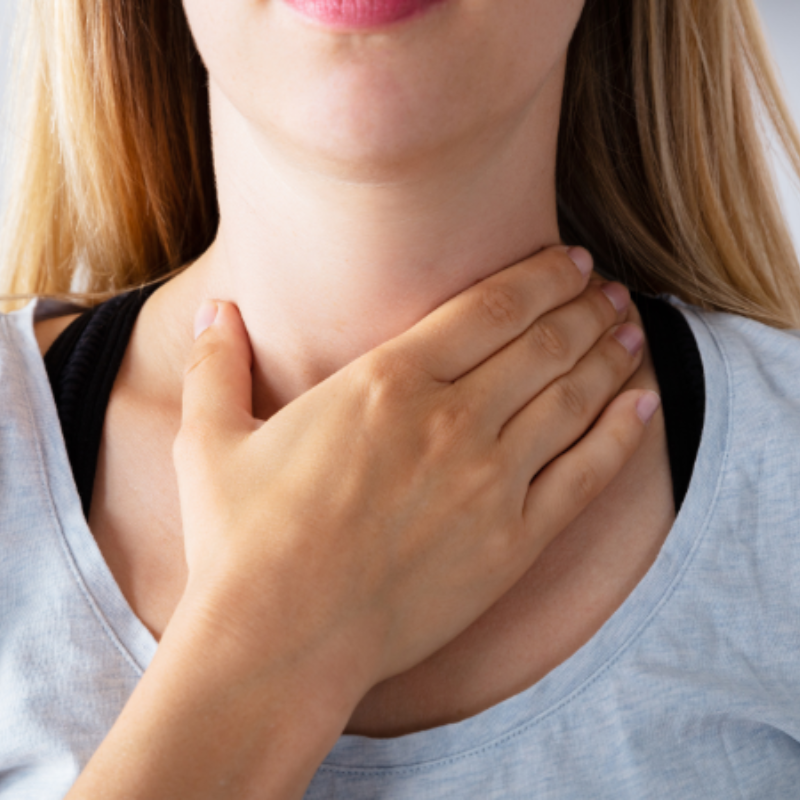 A woman is holding her hand to her neck