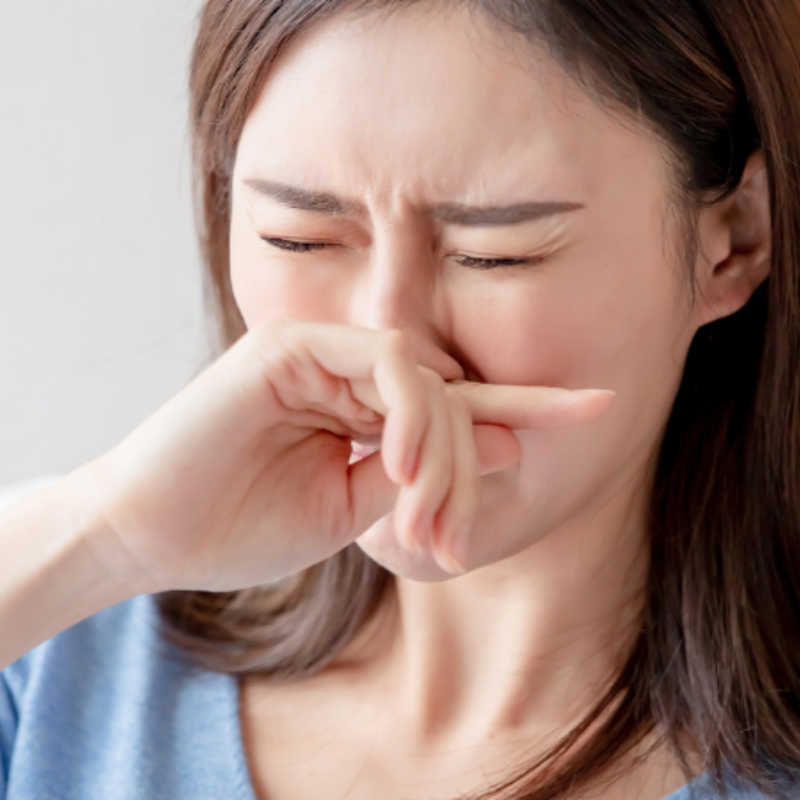 A woman is covering her nose with her hand.