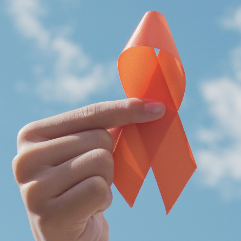 A person is holding an orange ribbon in their hand