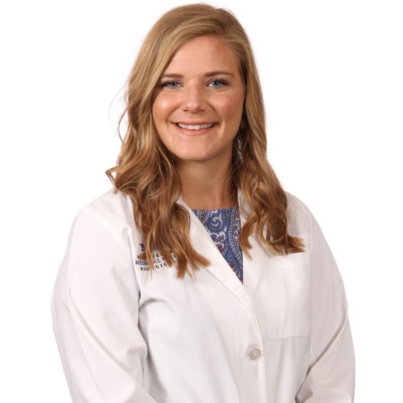 A woman in a white lab coat is smiling for the camera.