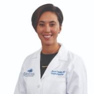 A woman in a white lab coat is smiling for the camera.