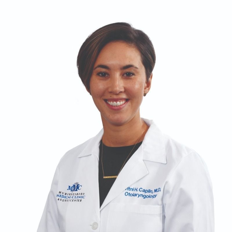 A woman in a white lab coat is smiling for the camera