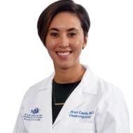 A woman in a white lab coat is smiling for the camera.