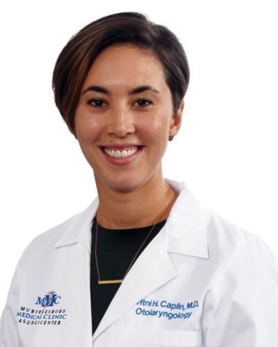 A woman wearing a white lab coat with a name written on it