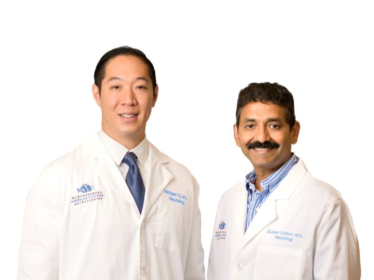 Two doctors are posing for a picture and one has a mustache