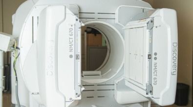 A ct scan machine is sitting in a room with its doors open.