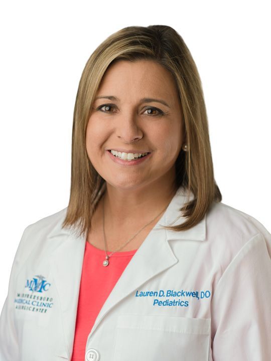 A woman in a white lab coat is smiling for the camera