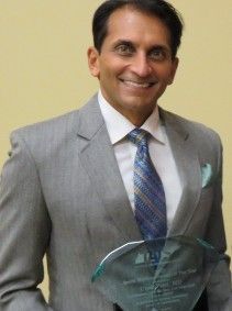 A man in a suit and tie is holding a trophy.