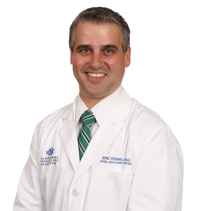 A man wearing a white lab coat and a green tie