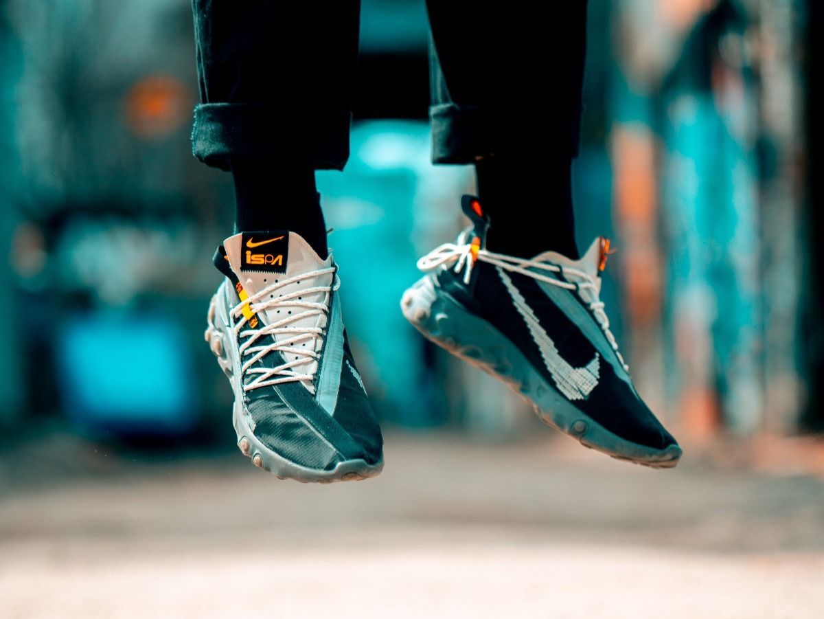 A person is jumping in the air wearing a pair of nike sneakers.