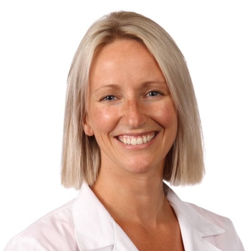 A woman in a white lab coat smiles for the camera
