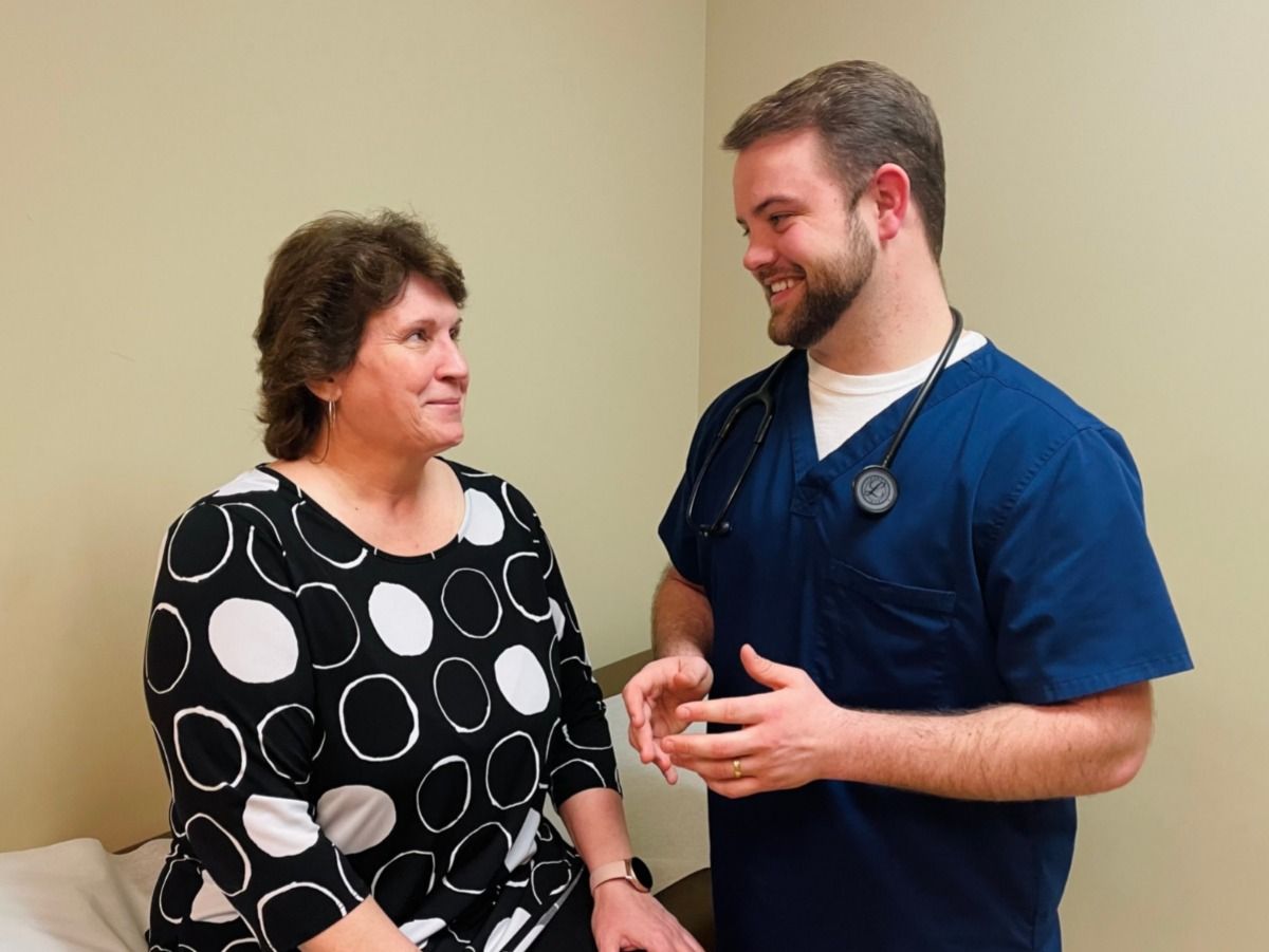 A man with a stethoscope is talking to a woman