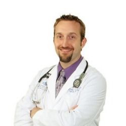 A doctor with a beard is wearing a white coat and a stethoscope around his neck.