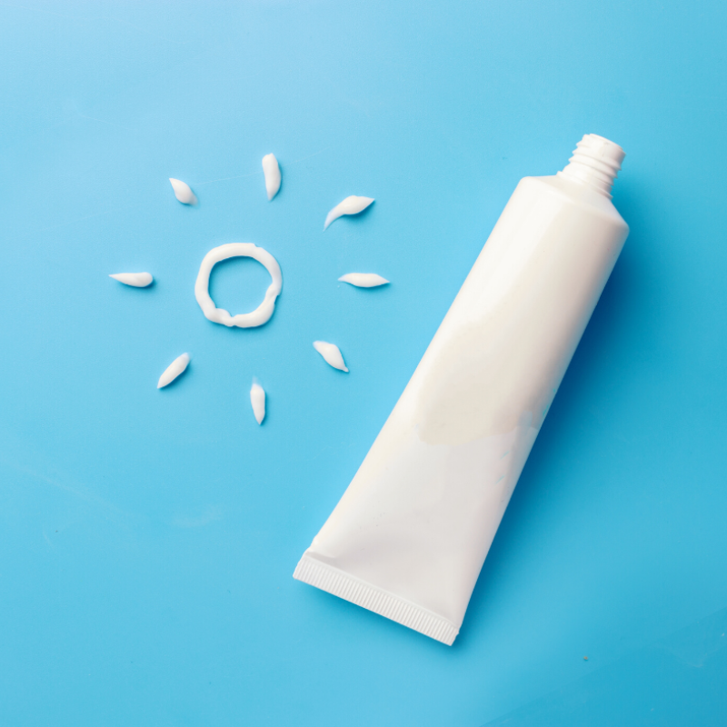 A tube of toothpaste and a sun made out of toothpaste on a blue background.